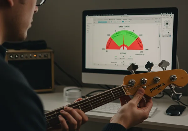 User tuning a bass with an online tuner on a screen