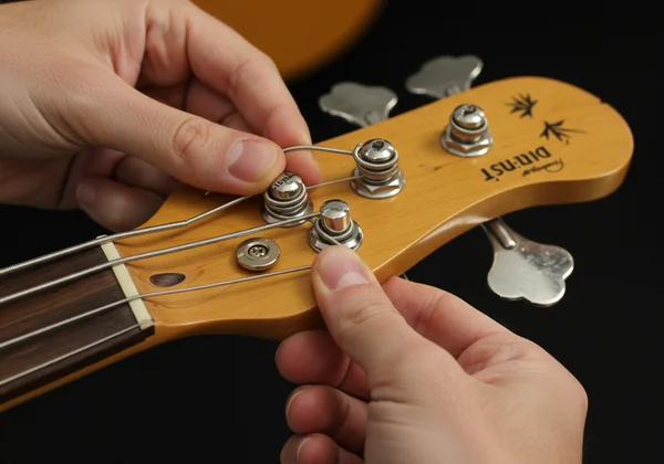 Hands demonstrating proper bass string winding technique.