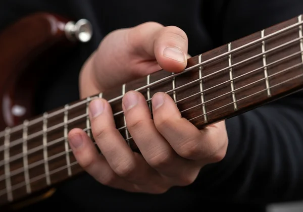 Bass player's left hand demonstrating correct fretting technique